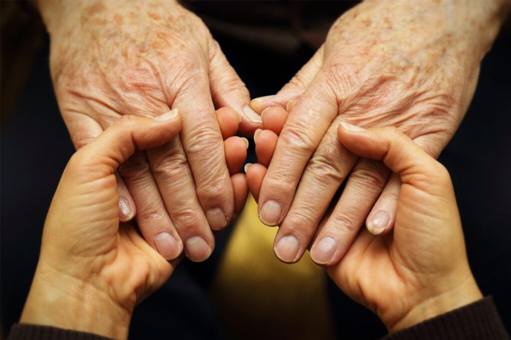 young person holding the hands of a senior