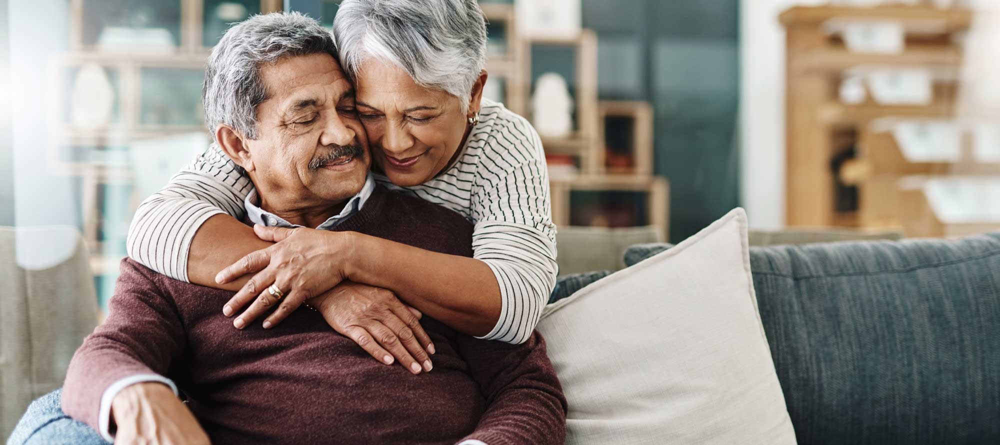 Senior couple hugging inside their retirement home