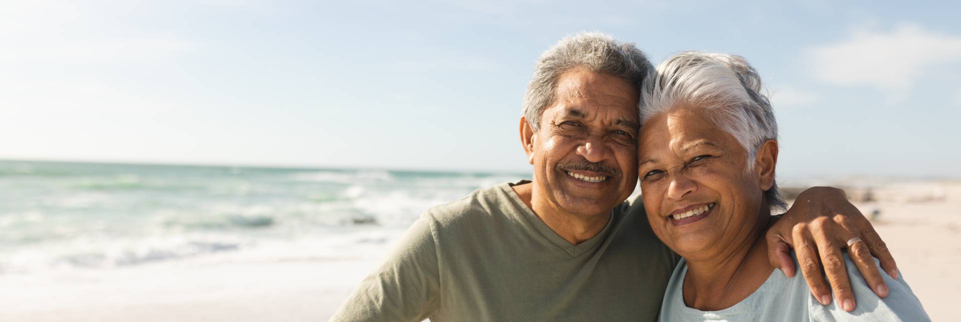 happy active seniors riding their bikes on the shoreline on a sunny day