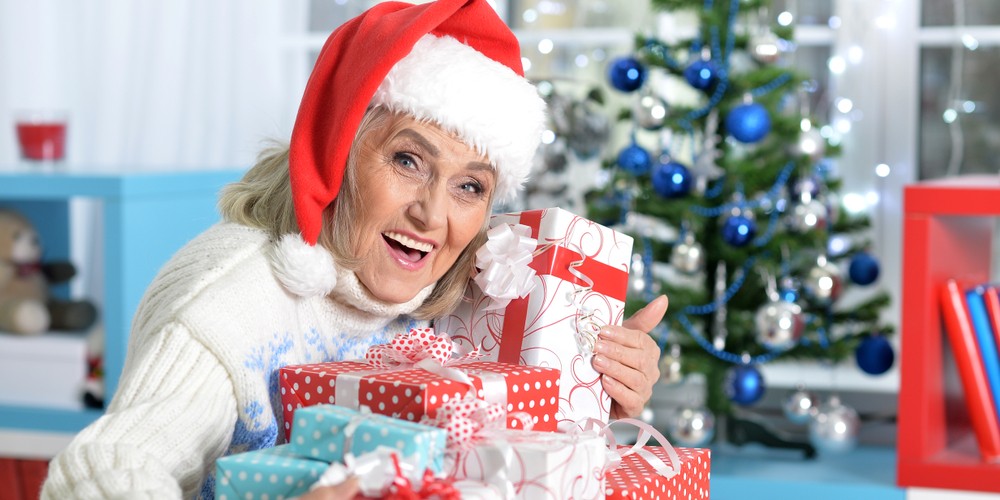 Happy senior woman in Santa hat with presents