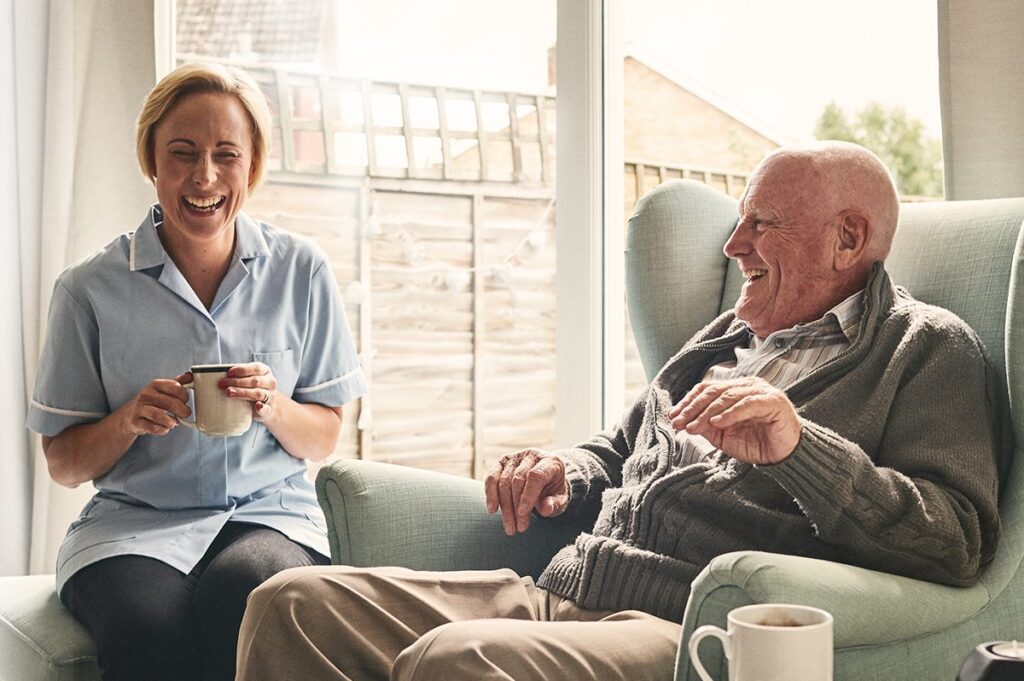senior man talking with a healthcare worker while drinking coffee