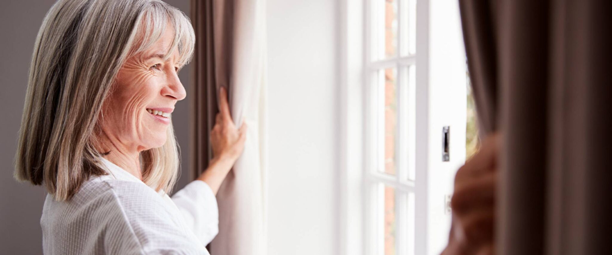 Senior woman looking out the window at her apartment