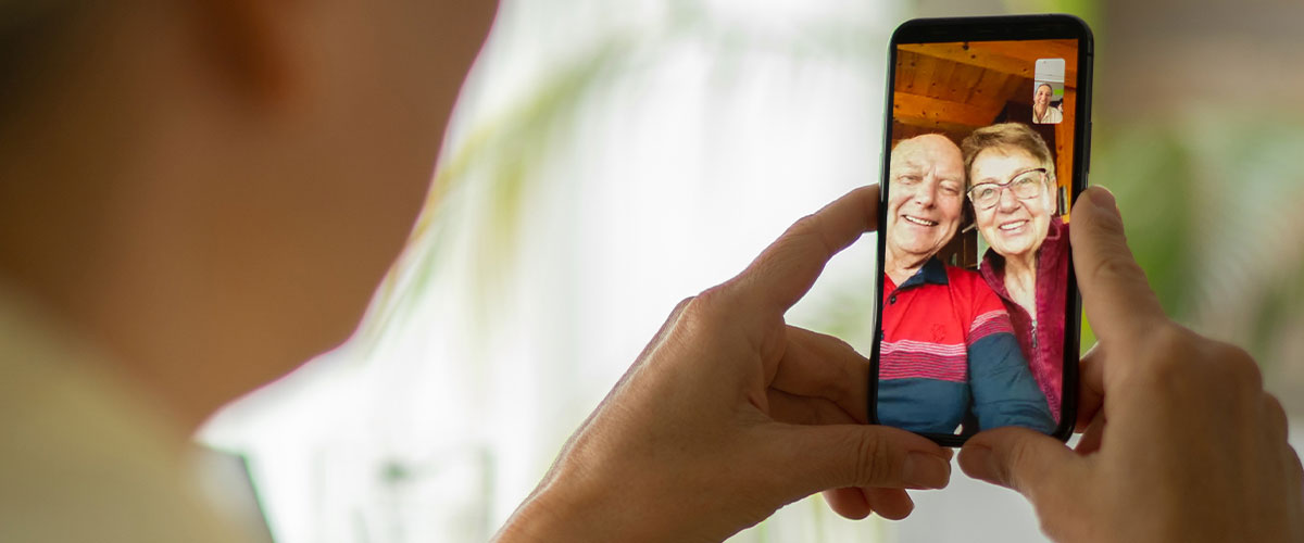 an elderly couple facetiming their child on an iphone