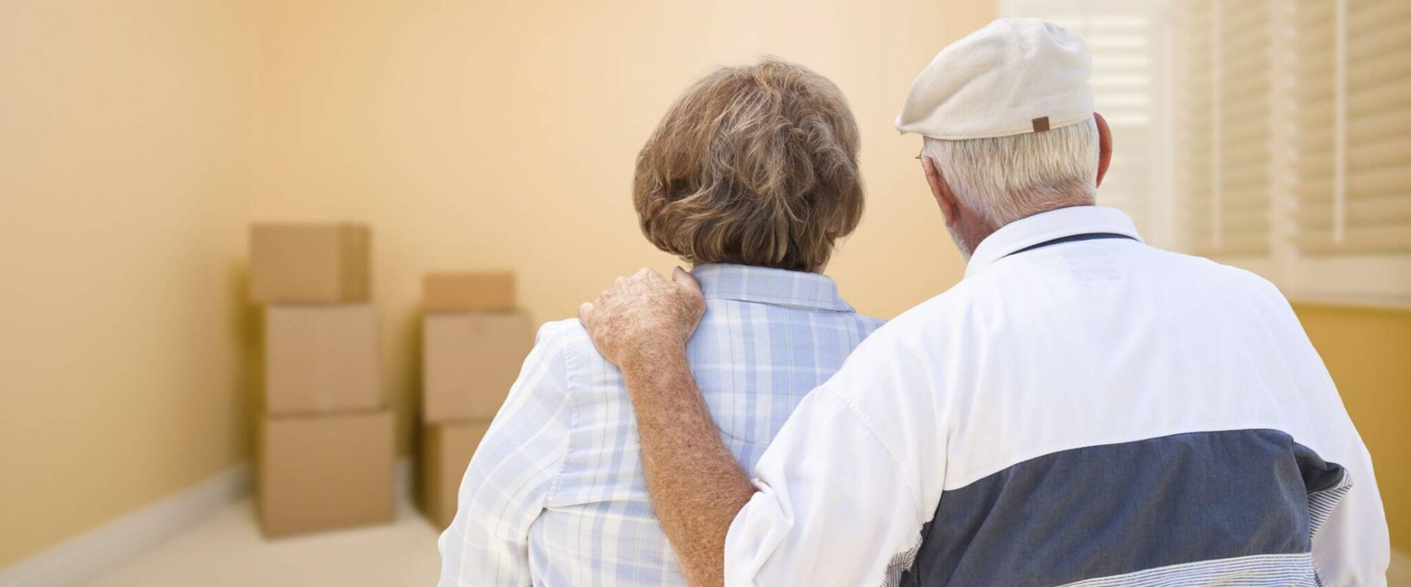 A senior man puts his arm around a senior woman as they begin to downsize to a senior apartment