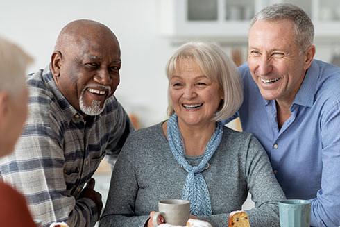 A group of seniors smile while holding coffee cups.