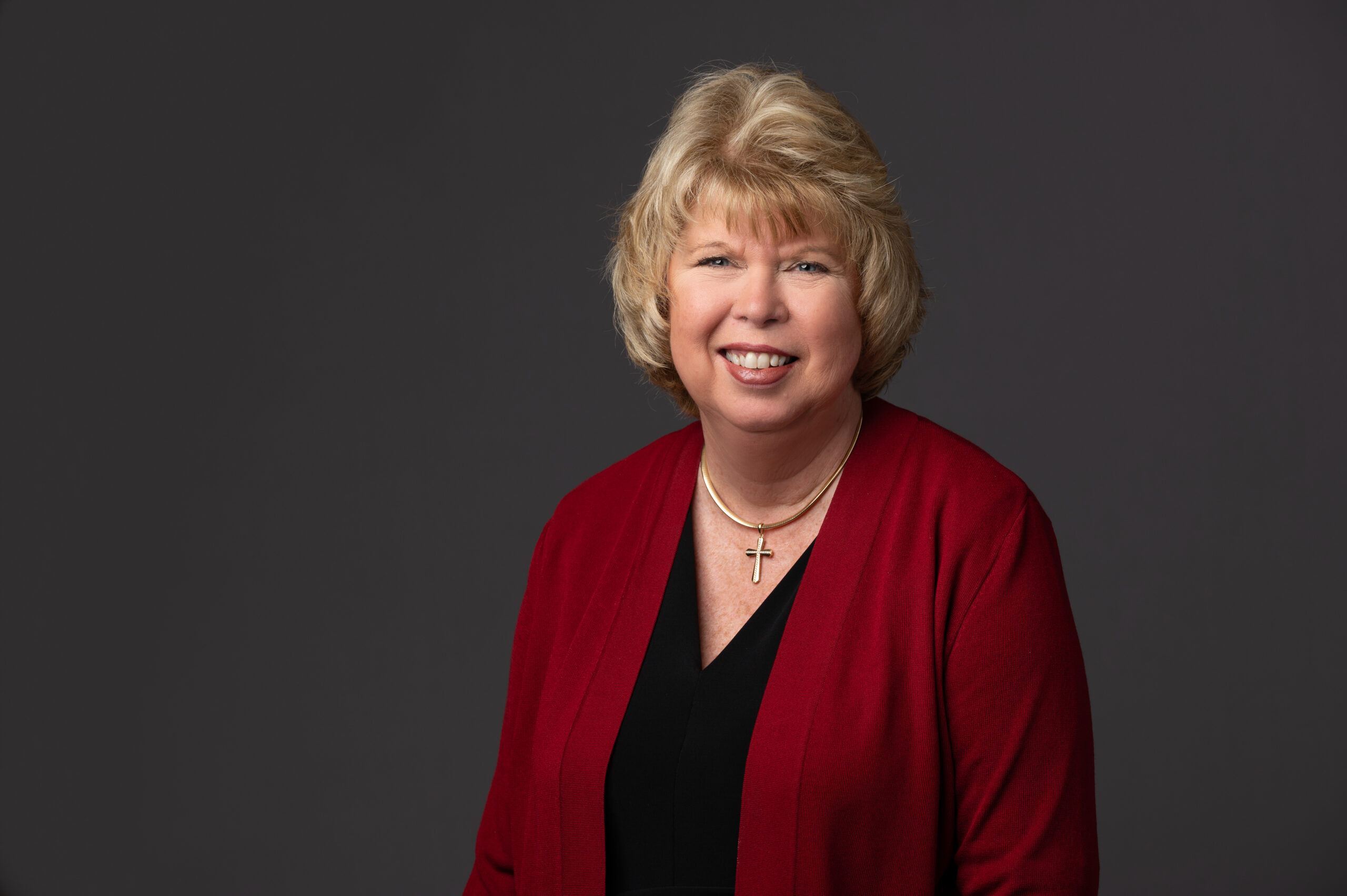 A photo of Wanda Petkiewicz, a woman wearing a red blazer and black shirt with a blonde bob cut