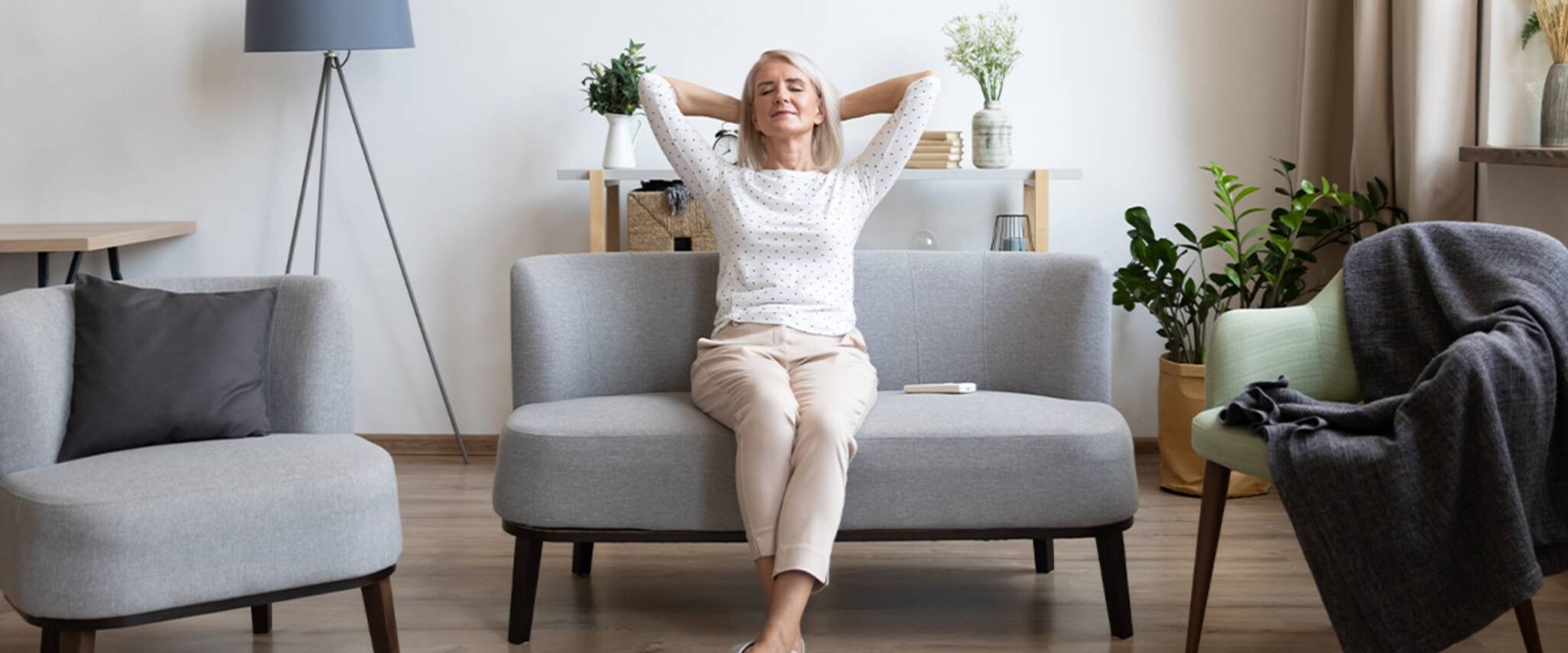 senior woman sitting on a sofa with her hands behind her head