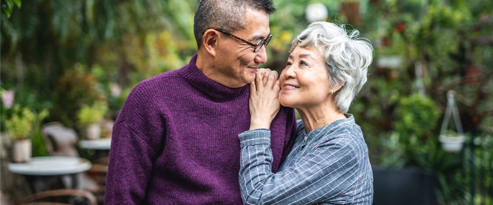 Elderly couple looking at one another outside smiling