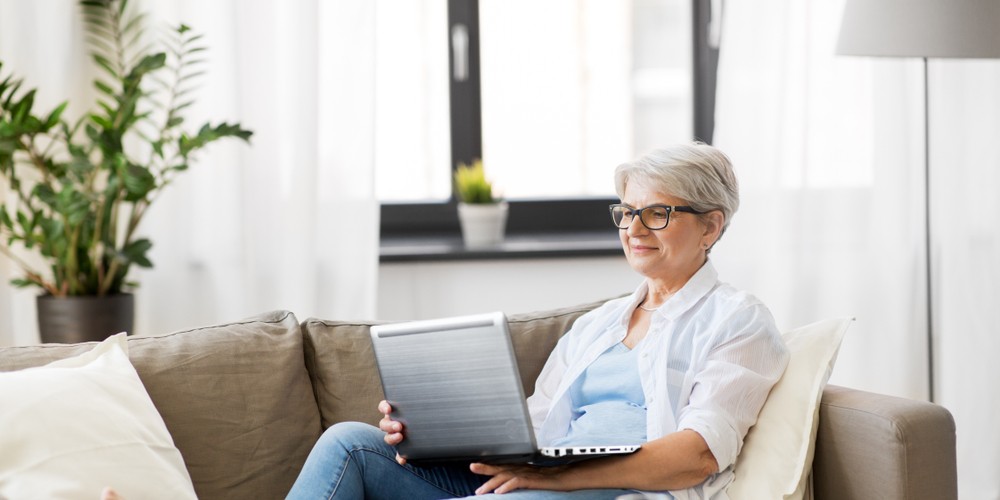 happy senior woman in glasses using her laptop computer
