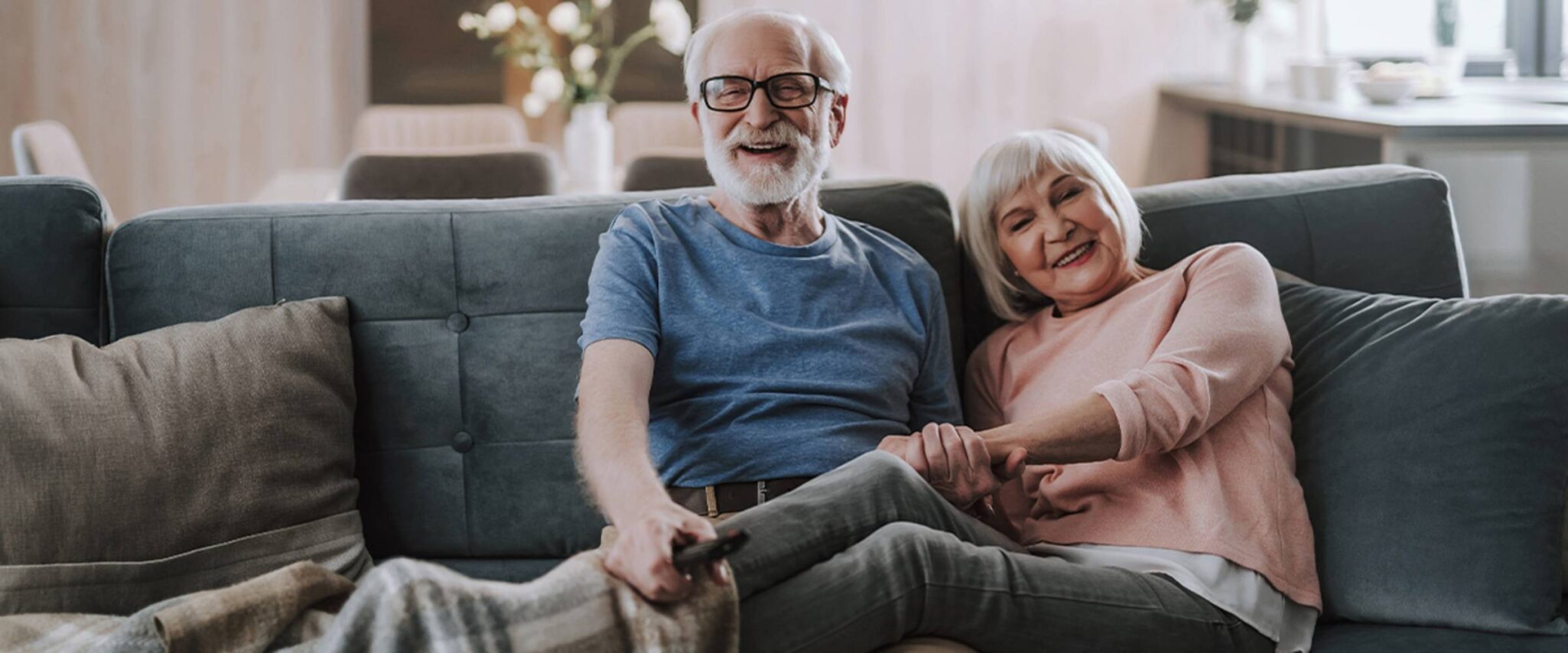 A senior couple, husband and wife, cuddle on the couch