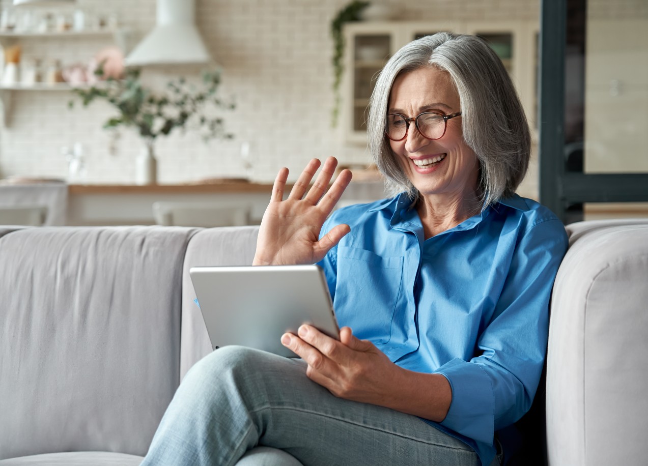 Senior video chatting with family on couch