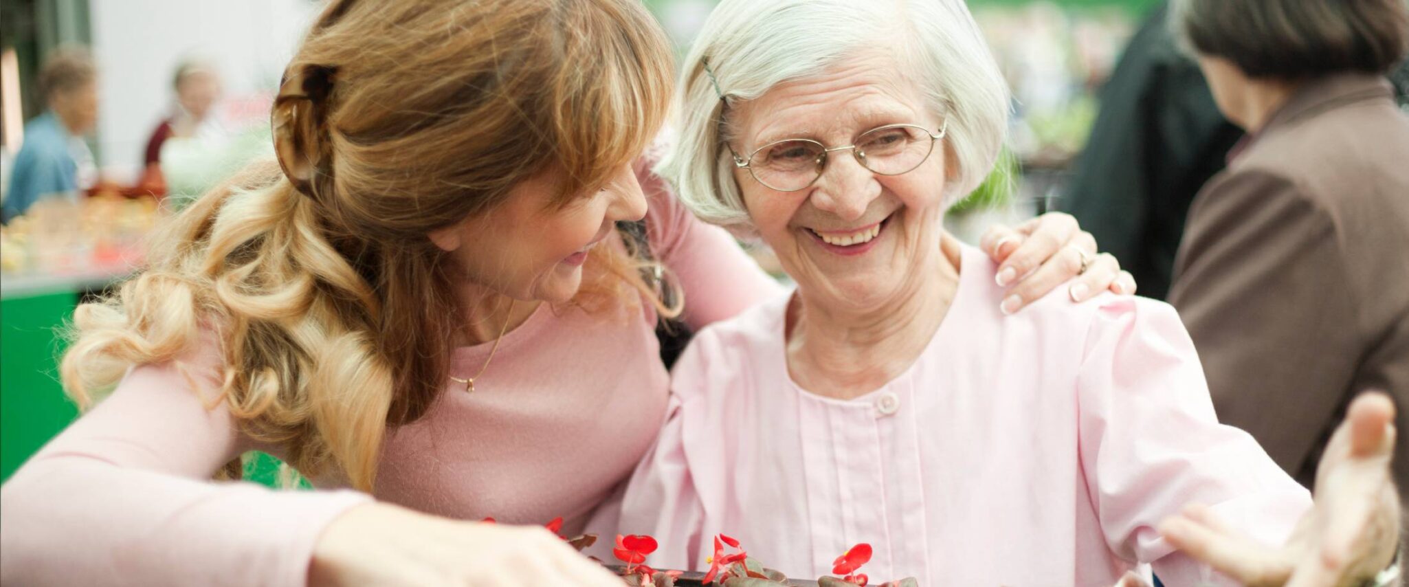 Elderly woman with her adult daughter looking at flowers