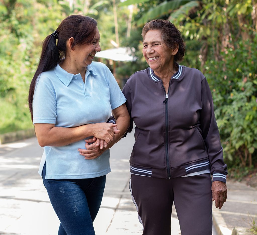 Adult woman supporting her elderly mother on a morning walk. Concept of active aging and positive retirement.